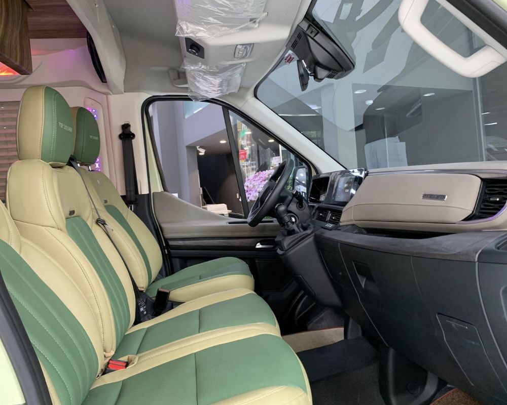 Green and beige leather seats inside a luxury van’s driver cabin.