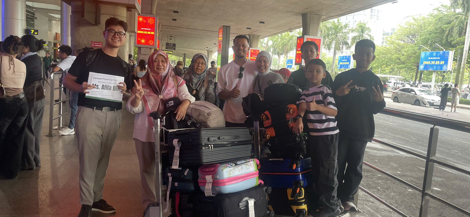 Group-of-tourists-taking-a-photo-with-a-driver-holding-a-welcome-sign-at-the-airport