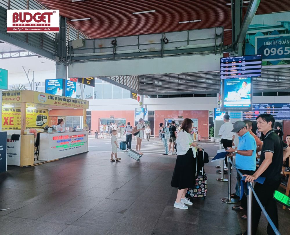 A-women-pulling-suitcases-near-the-airport-transfer-service-counters-under-the-Arrivals-screen-at-Cam-Ranh-Airport