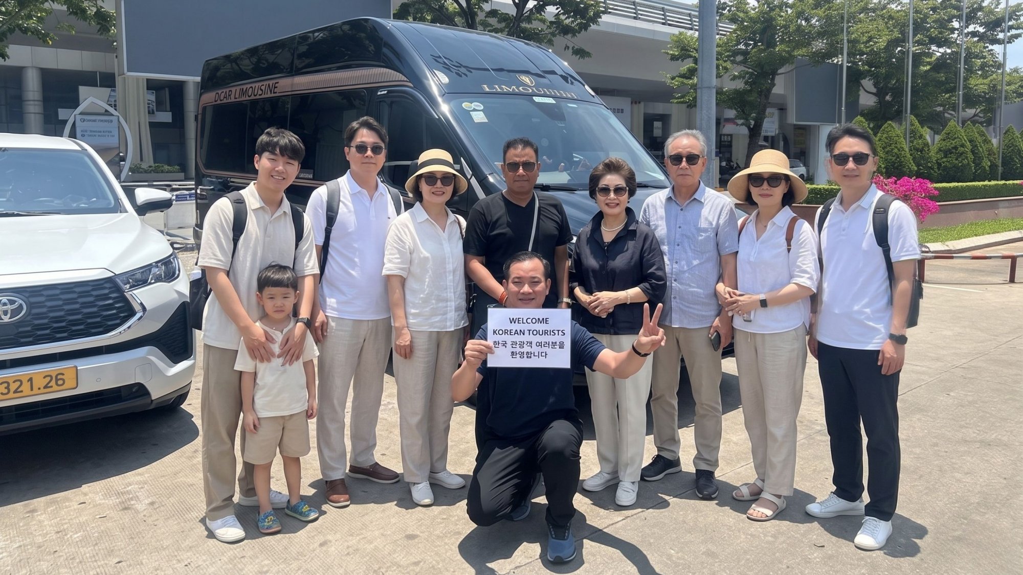 Group-of-Korean-tourists-posing-with-a-black-DCAR-limousine-and-driver-holding-a-welcome-sign-at-the-pickup-point-01
