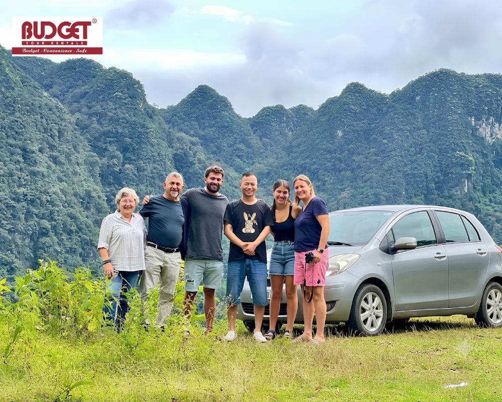 Group-of-tourists-and-our-driver-posing-next-to-a-private-car-with-beautiful-karst-mountain-scenery-in-Sapa-Vietnam