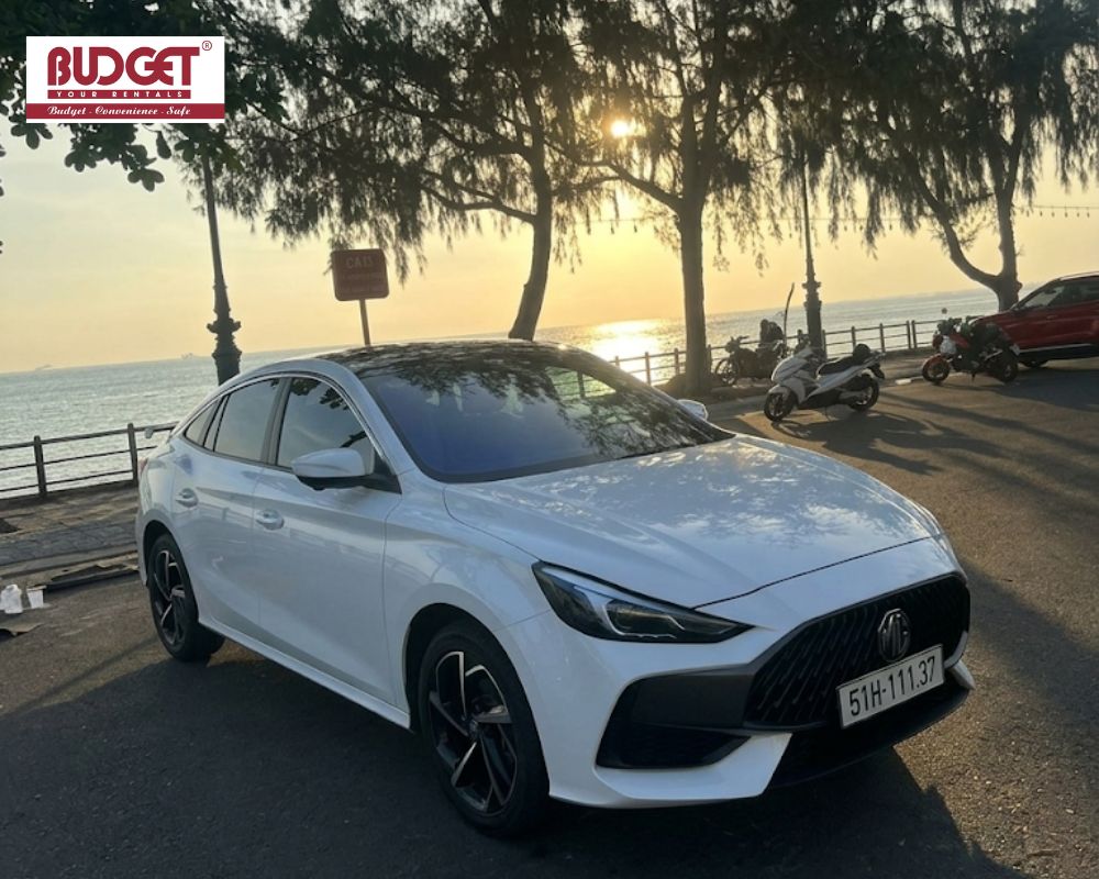 Modern-white-4-seat-MG5-parked-on-a-scenic-coastal-road-at-sunset