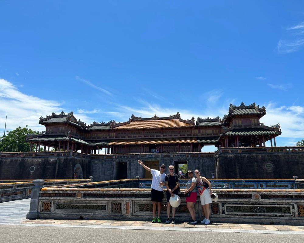 The group stands in front of the beautifully ornate gate of the Imperial City in Hue