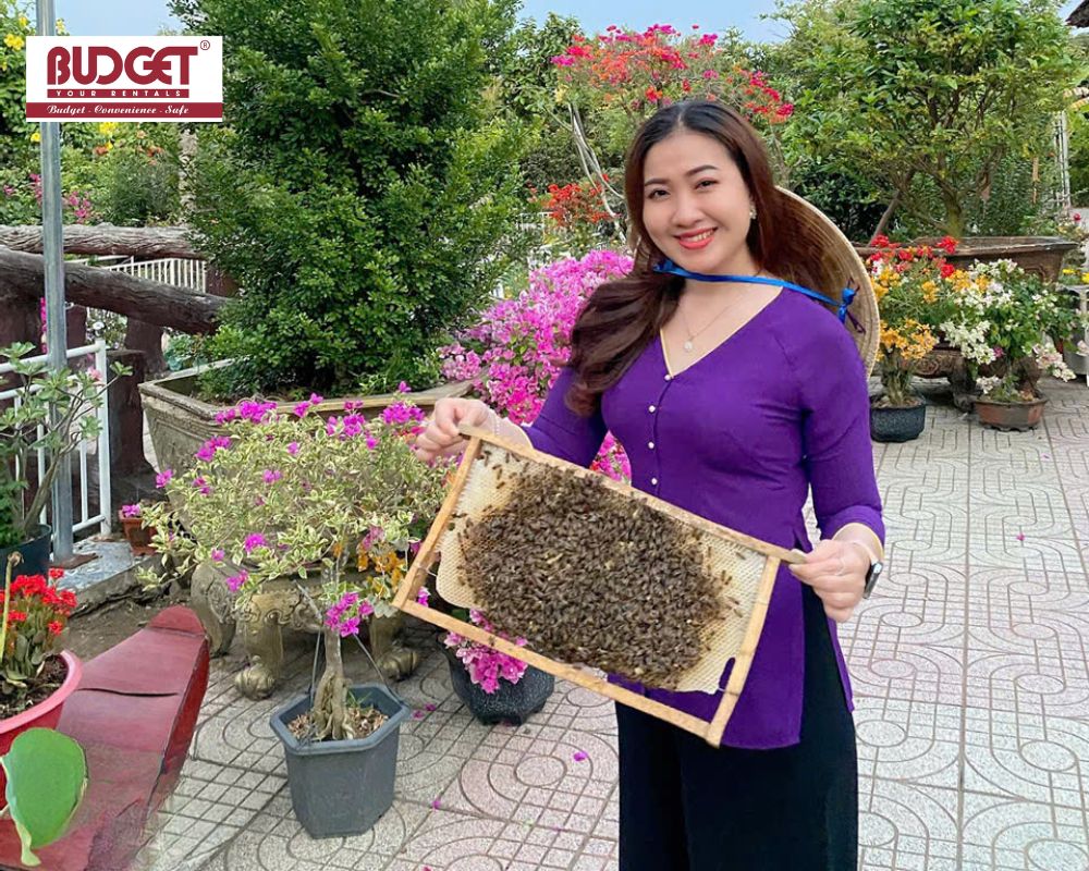 A-woman-holding-a-honeycomb-frame-during-a-honey-bee-farm-tour-in-Ben-Tre