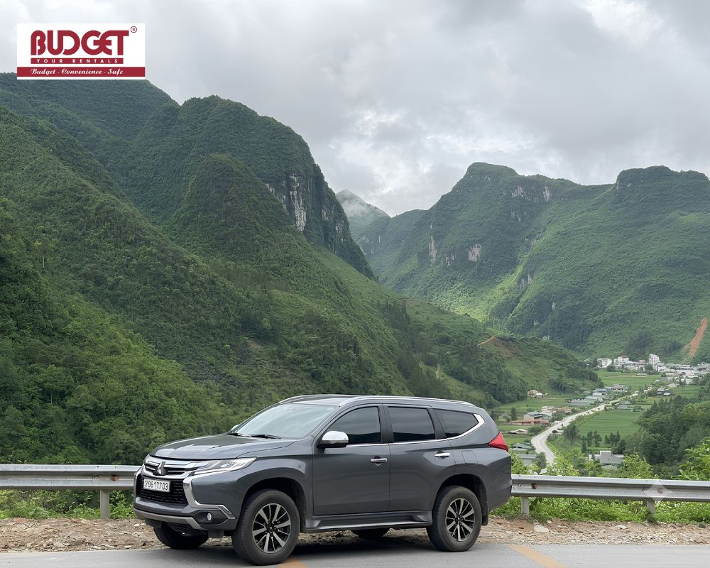 Dark-grey-Mitsubishi-SUV-parked-along-a-winding-cliffside-highway-in-Ha-Giang