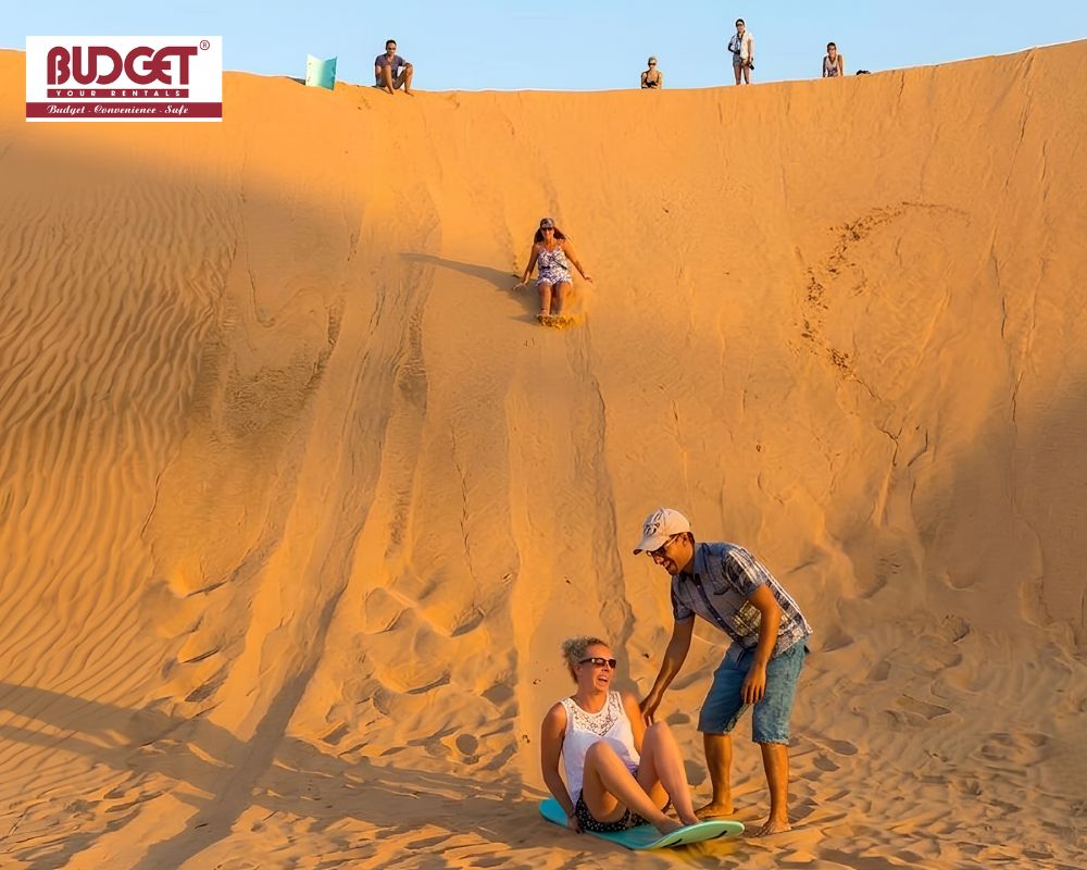 Foreign-tourists-enjoying-sandboarding-down-the-massive-golden-sand-dunes-of-Quang-Phu