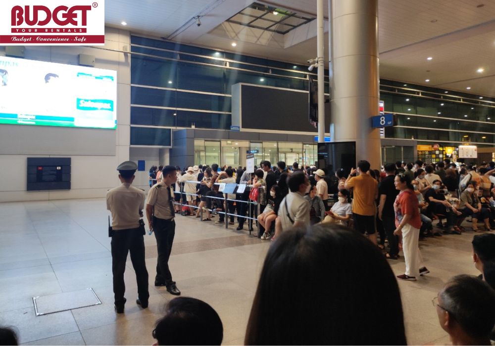 A crowd of people waiting behind barriers at the arrivals hall of Tan Son Nhat Airport