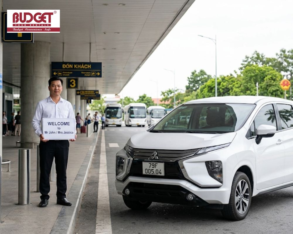 Our-chauffeur-holding-a-personalized-welcome-sign-next-to-a-white-Mitsubishi-MPV-at-Cam-Ranh-International-Airport
