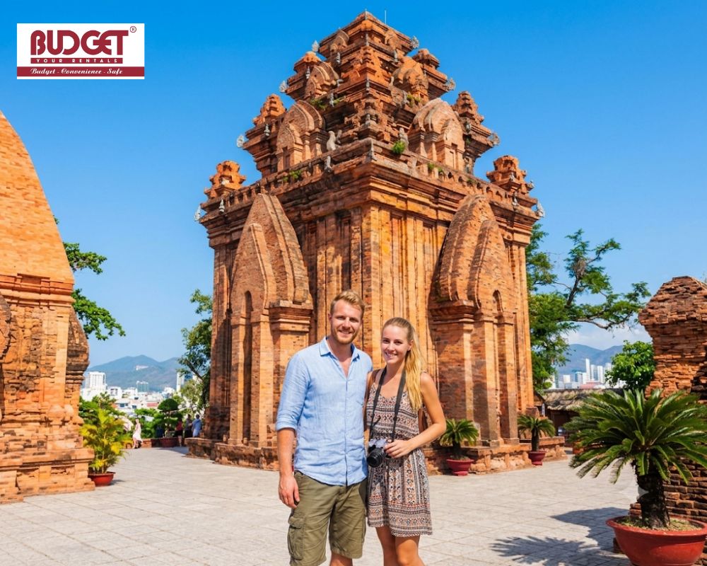 Smiling-foreign-tourist-couple-posing-in-front-of-the-ancient-red-brick-Ponagar-Cham-Towers
