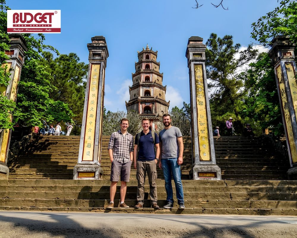 Three-male-travelers-took-a-picture-in-front-of-Phuoc-Dien-Tower-at-Thien-Mu-Pagoda-in-Hue