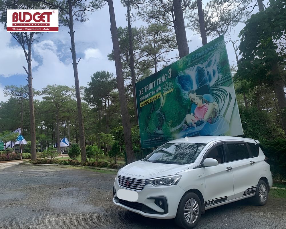 White-Suzuki-MPV-parked-beneath-tall-pine-trees-at-the-Datanla-Waterfall-alpine-coaster-entrance-at-Da-Lat