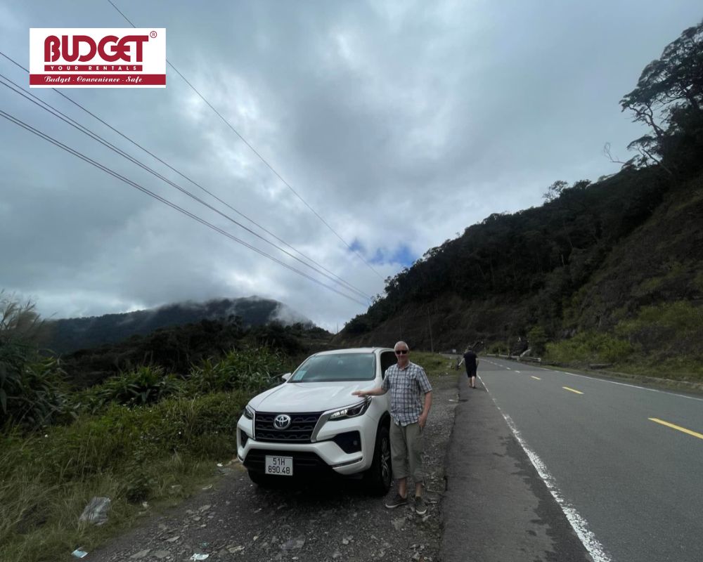 Our-traveler-took-a-picture-next-to-our-white-7-seat-Toyota-parked-along-Khanh-Le-Pass