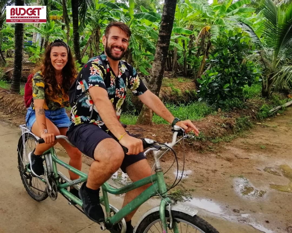 Travelers enjoy a fun double-biking experience along the peaceful, green village paths of Con Phung
