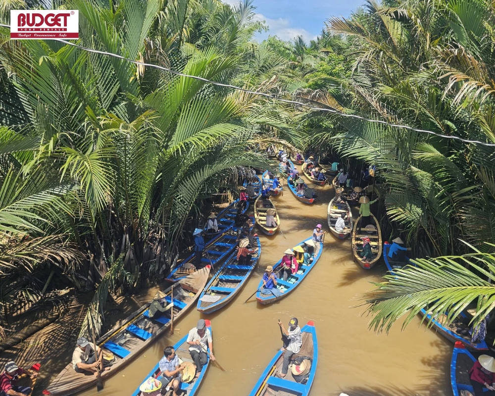 Travelers experience a hand-rowed sampan cruise through shaded water-coconut canals of the Mekong Delta
