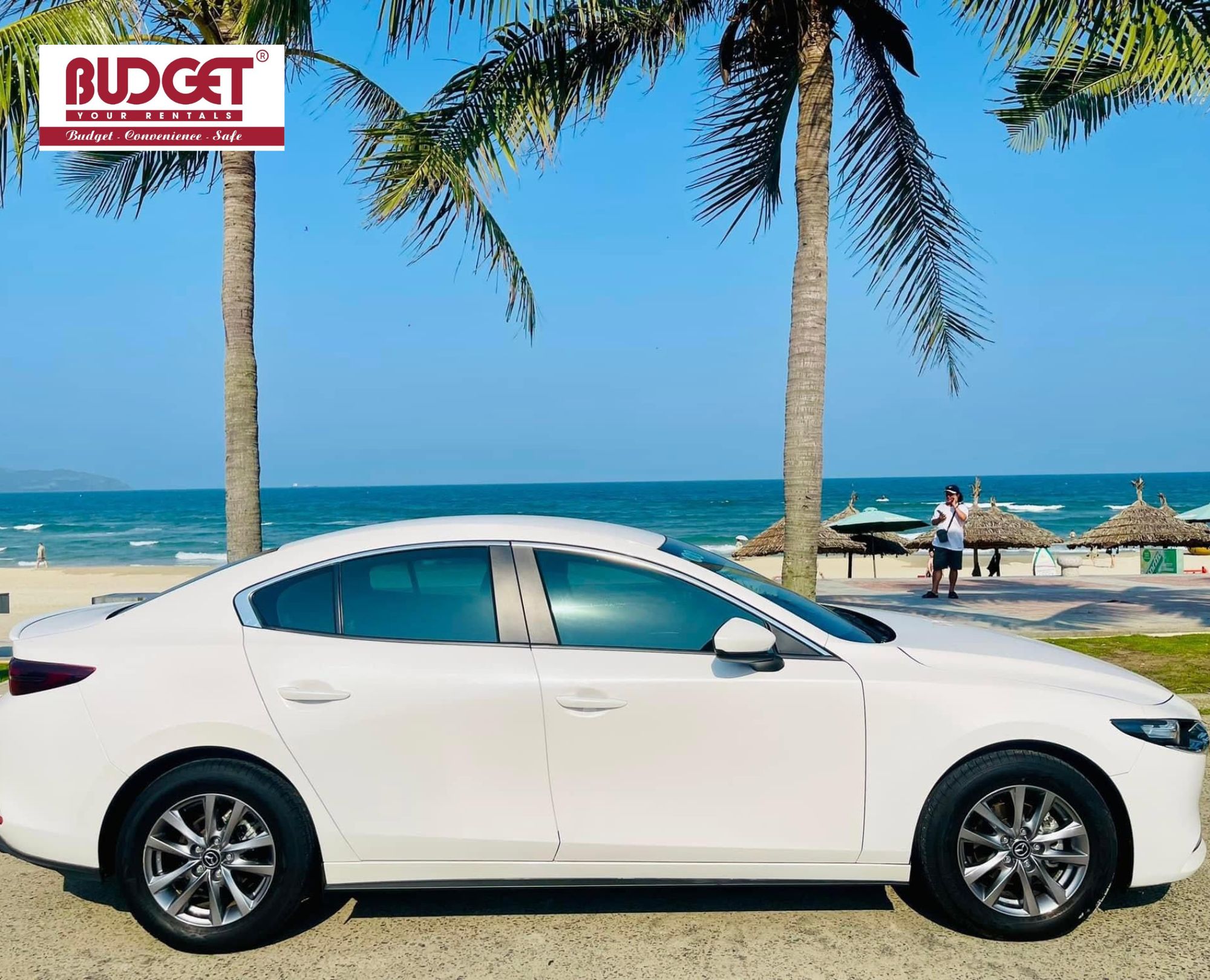 White-sedan-parked-by-the-beach-with-palm-trees-and-blue-sea