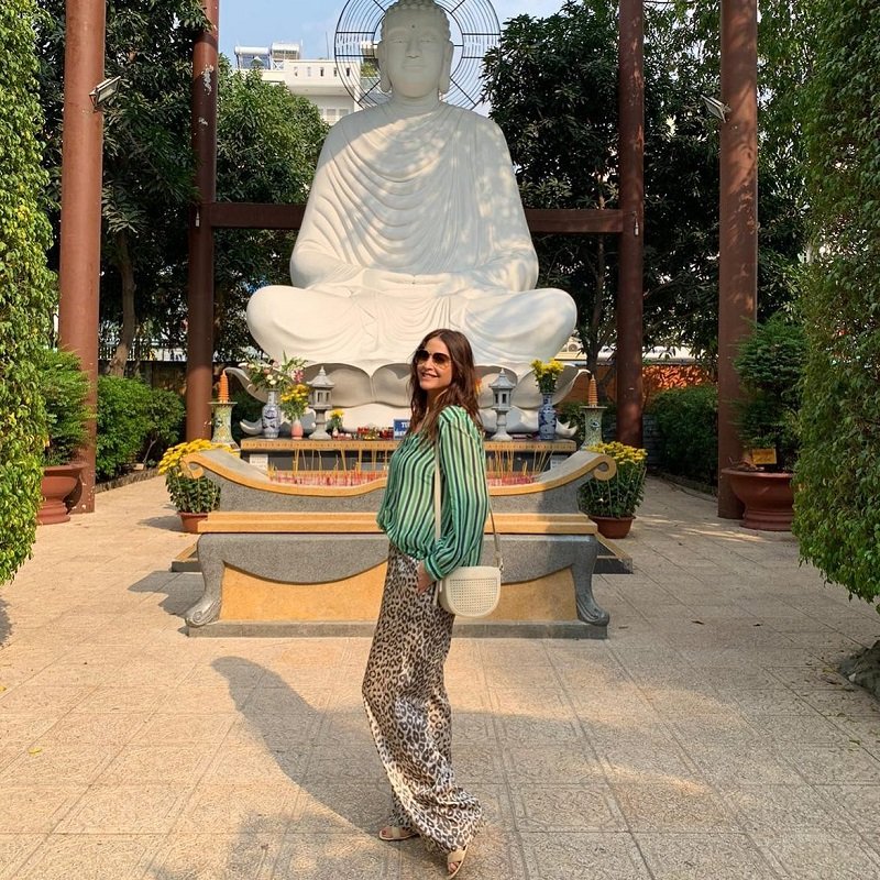 The girl taking pictures next to the Buddha statue of the temple