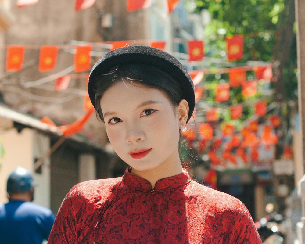 Vietnamese woman in Ao Dai with flags in Hanoi