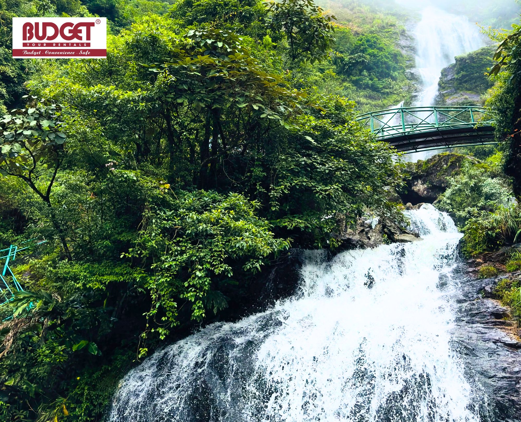 Majestic-Silver-Waterfall-that-cascades-down-lush-green-mountains-under-a-arched-footbridge