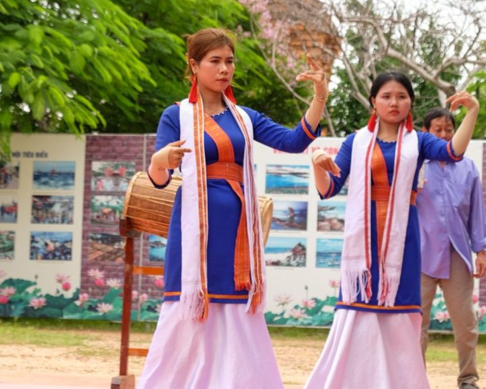 Cham dancers performing a traditional dance in vibrant costumes at the Kate festival