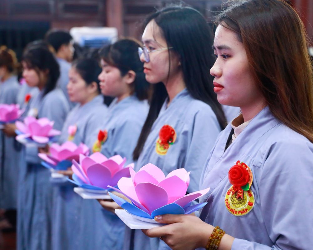 Participants in traditional robes hold lotus lanterns during Vu Lan Festival