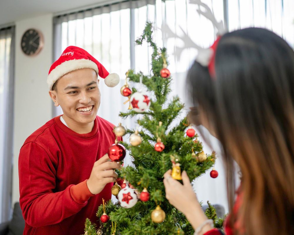 Man decorating christmas tree with his girlfriend