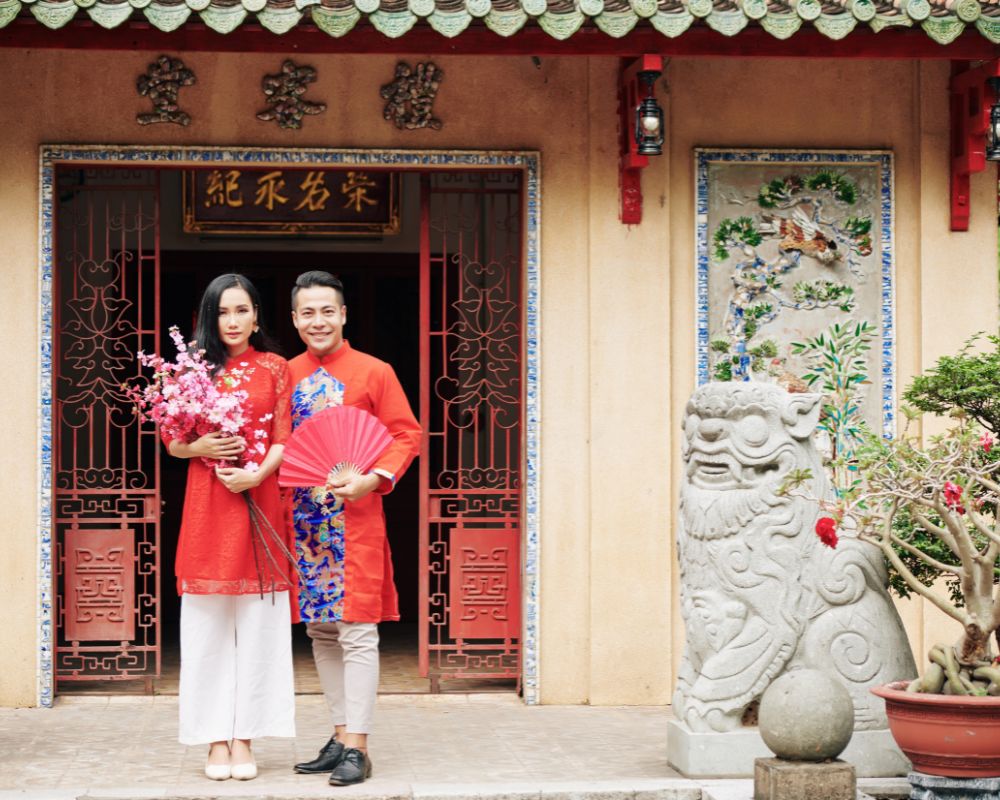 The ouple in traiditional dresess standing at temple doors