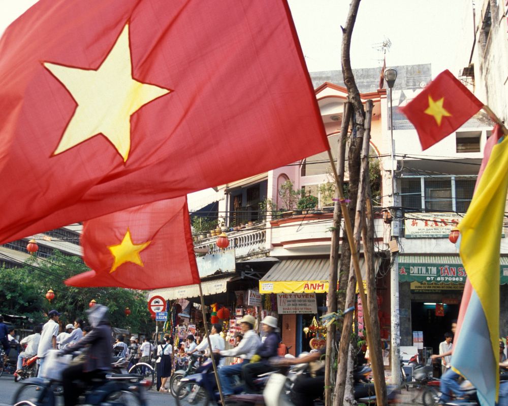 Vietnamese flag and people on street by buildings in city